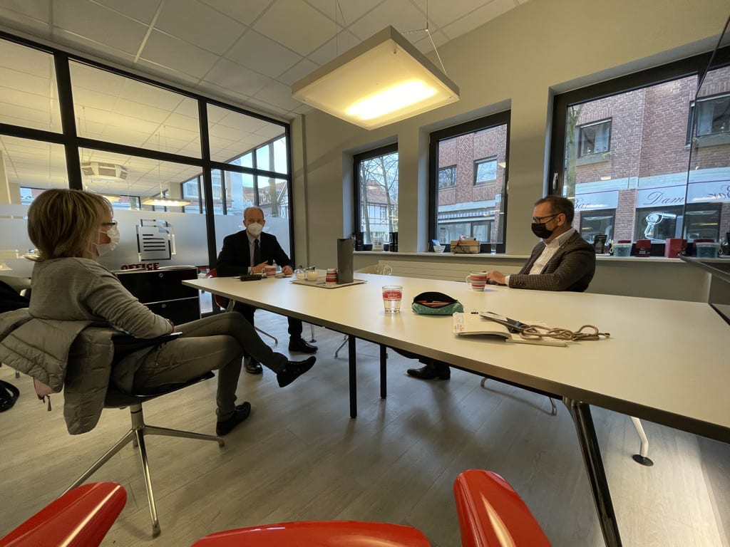 Menschen im Gespräch an einem Tisch im Besprechungsraum.