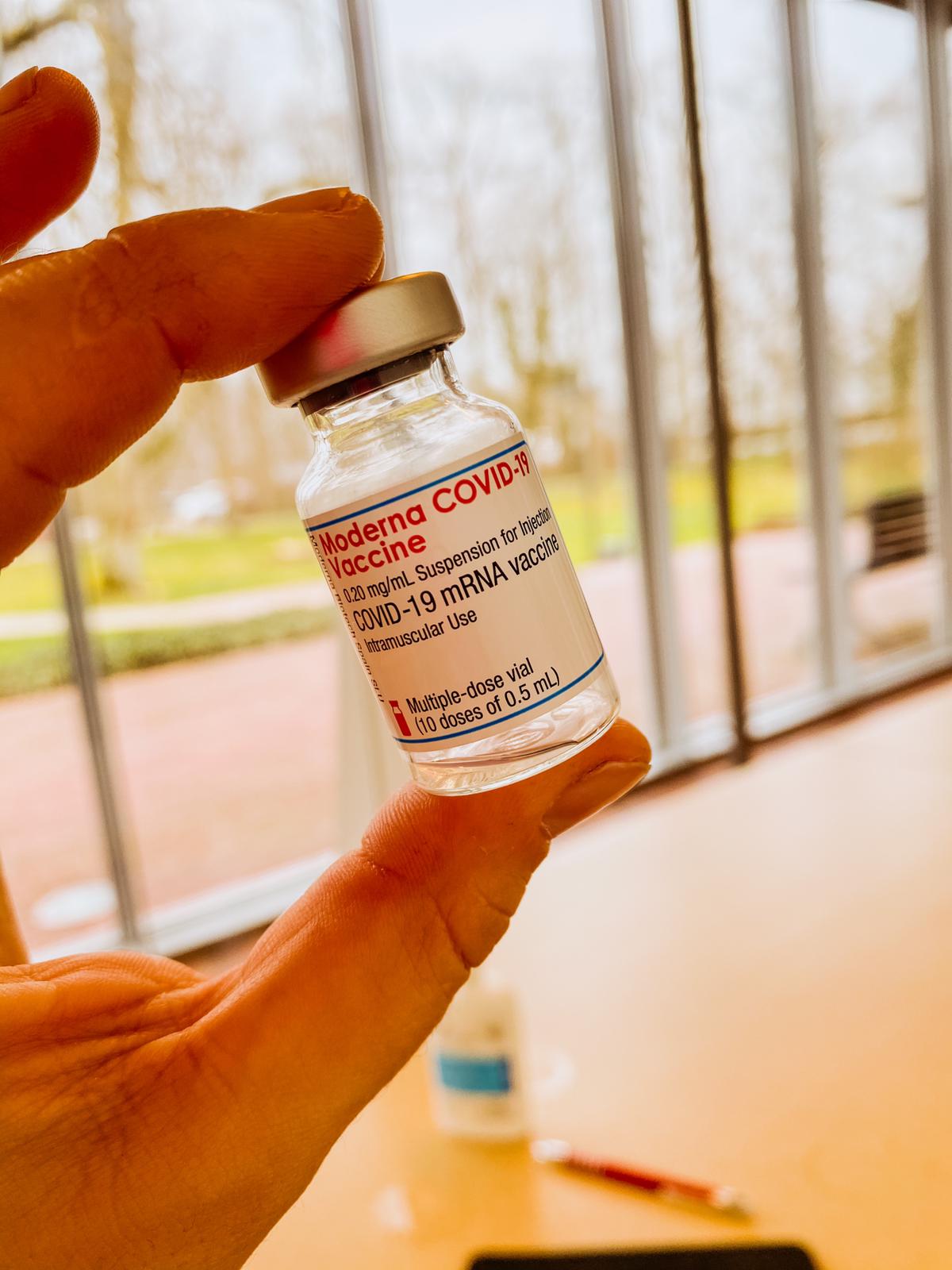 In den Alexianer Werkstätten sind die Impfungen gegen Corona gestartet. Eine leere Ampulle des Impfstoffes wird in Händen gehalten.