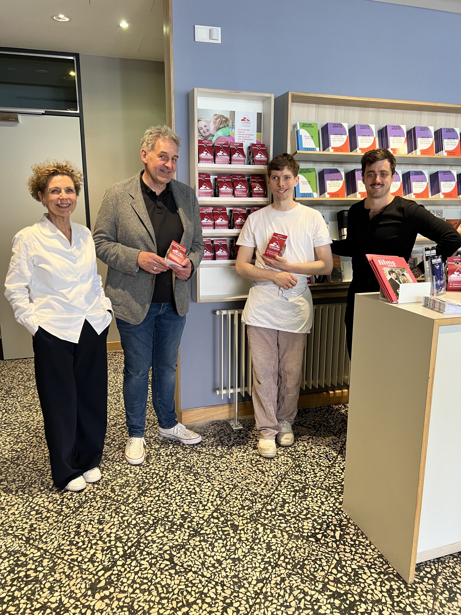 Ab sofort haben die beliebten Pelikanplätzchen der Alexianer ihr ganz eigenes Verkaufsregal an der Theaterkasse des Theaters Münster. Dr. Martina Klein (Fundraising der Alexianer), Andreas Menke, stellv. Verwaltungsdirektor vom Theater Münster, Jonas (Alexianer-Bäckerei) und Marcel Guthier (Öffentlichkeitsarbeit Theater Münster) freuen sich riesig über diese Kooperation. 
